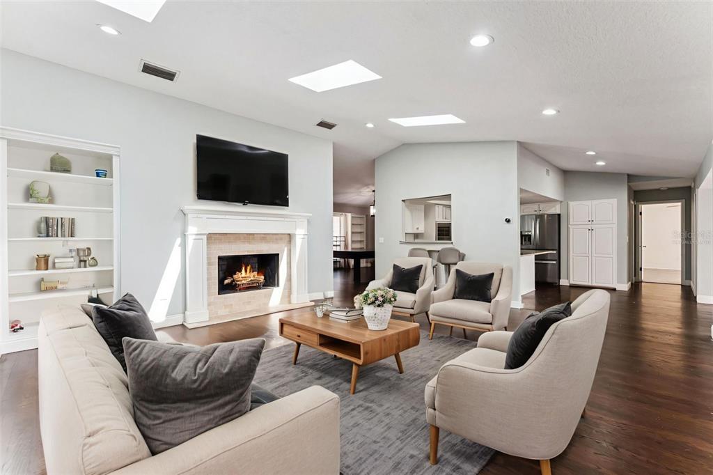 A living room features a fireplace, a mounted television, skylights, and light-colored furniture — 448 STONEWOOD LANE, MAITLAND, FL