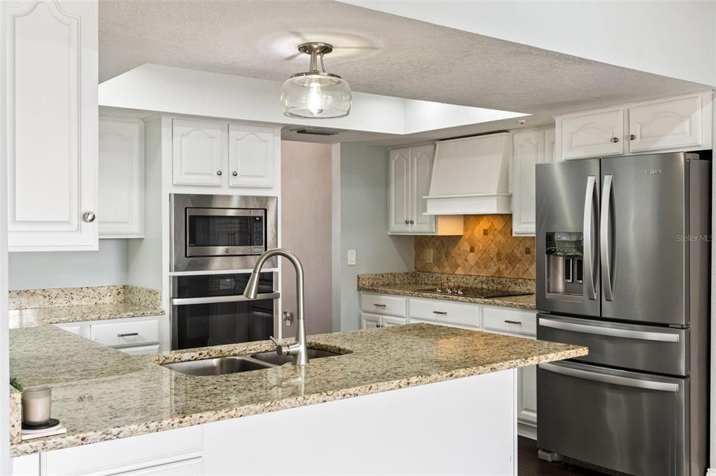 A kitchen with white cabinets, granite countertops, stainless steel appliances, and a central island — 448 STONEWOOD LANE, MAITLAND, FL