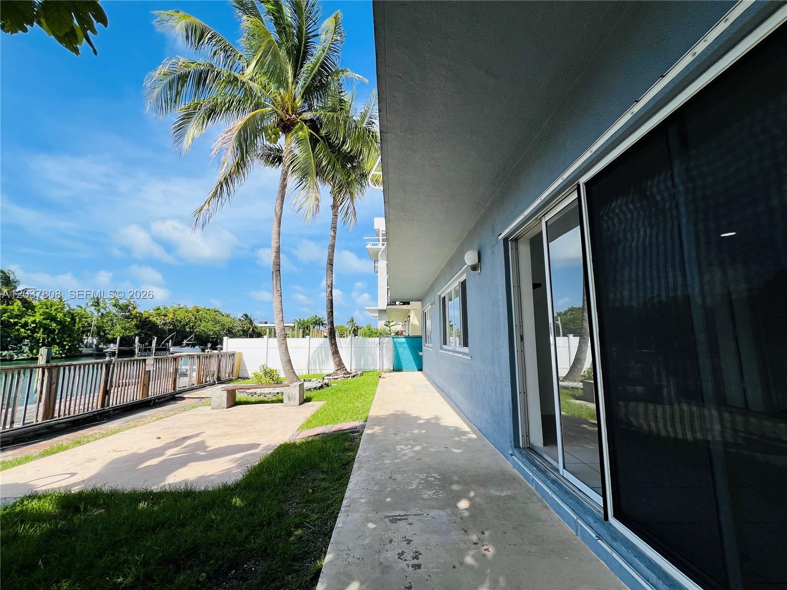 A blue house exterior features a concrete patio, a lawn, and a waterfront wooden deck — 2033 Calais Dr # 5, Miami Beach FL 33141, MIAMI BEACH, FL