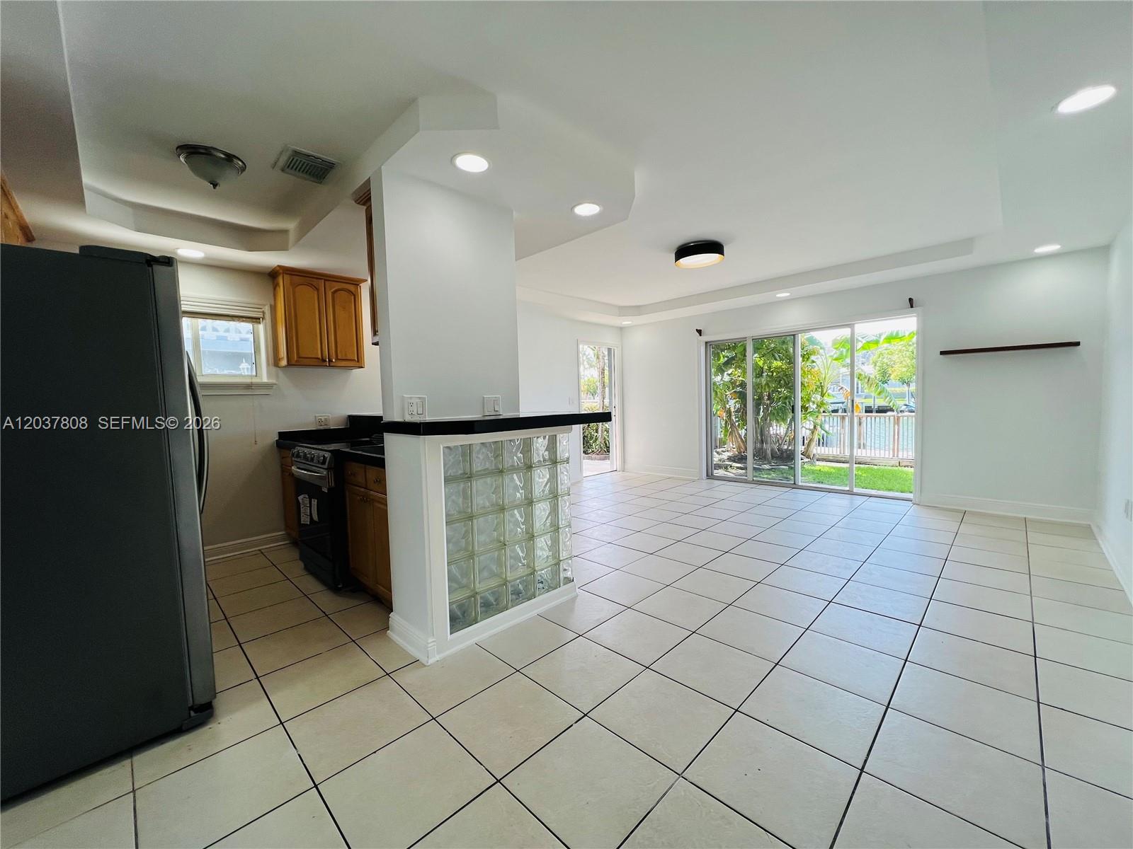 A kitchen with a glass block breakfast bar opens into a tiled living area — 2033 Calais Dr # 5, Miami Beach FL 33141, MIAMI BEACH, FL