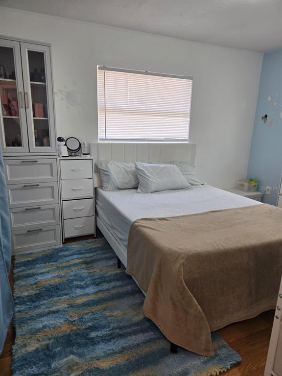 A bedroom features a bed with a white headboard, a tall storage cabinet, and blue rug — 459 WATER ROAD, OCALA, FL