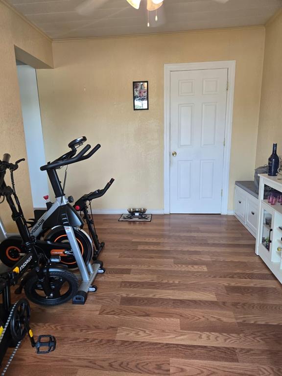 A room with wood-look flooring, two stationary exercise bikes, a white door, and built-in cabinetry — 459 WATER ROAD, OCALA, FL