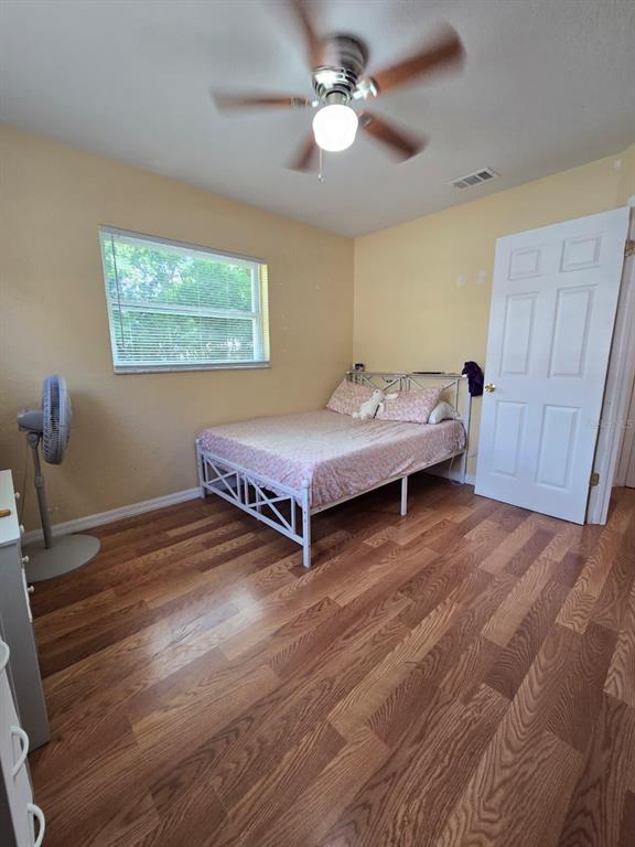 A bedroom features wood-look flooring, a ceiling fan, a window with blinds, and a bed — 459 WATER ROAD, OCALA, FL