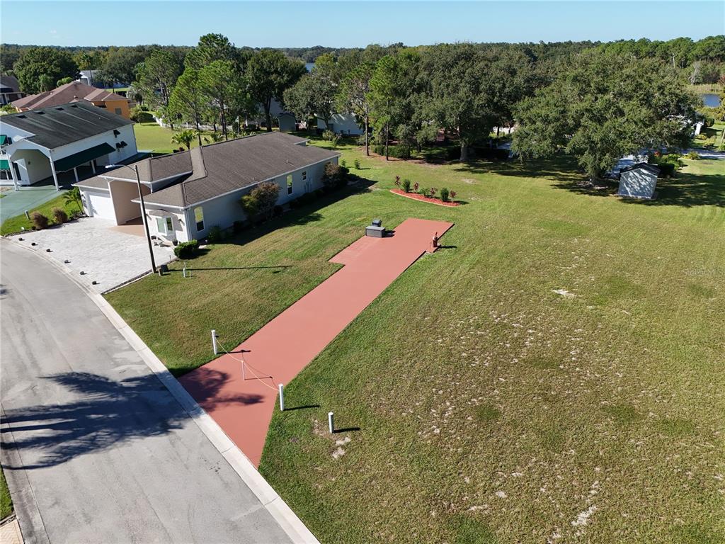 An aerial view shows a house with a long, red-painted driveway leading to a patio — 1052 CARAVAN LOOP, POLK CITY, FL