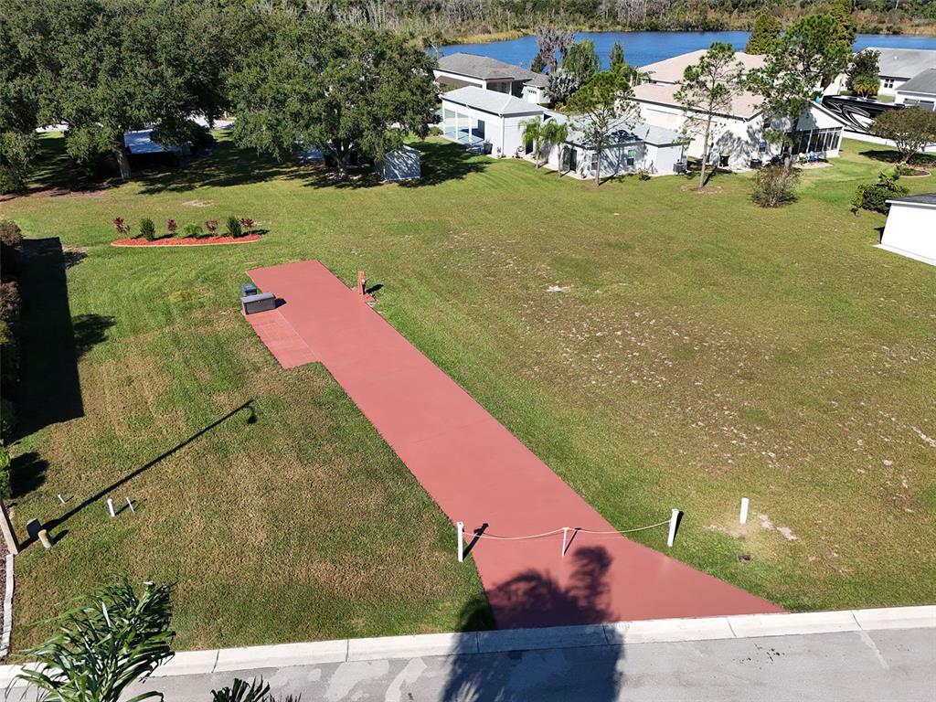 An aerial view shows a red concrete driveway extending into a large, grassy residential lot — 1052 CARAVAN LOOP, POLK CITY, FL