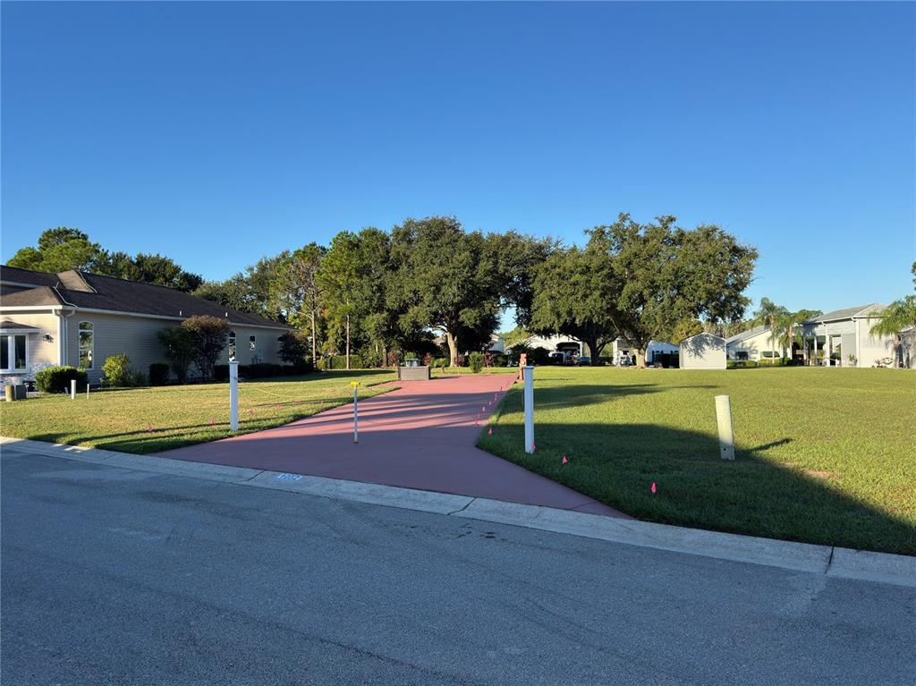 A paved driveway leads to a vacant grassy lot between two residential houses — 1052 CARAVAN LOOP, POLK CITY, FL