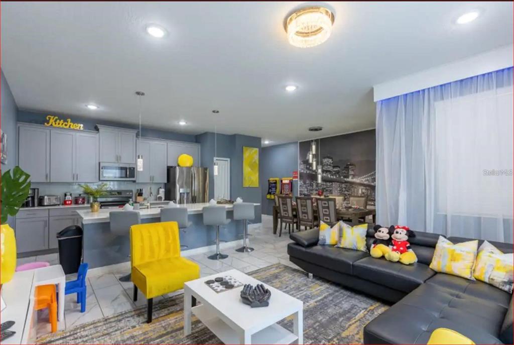 An open-concept kitchen, dining area, and living room with gray cabinets and yellow accents — 1563 PLUNKER DRIVE, DAVENPORT, FL