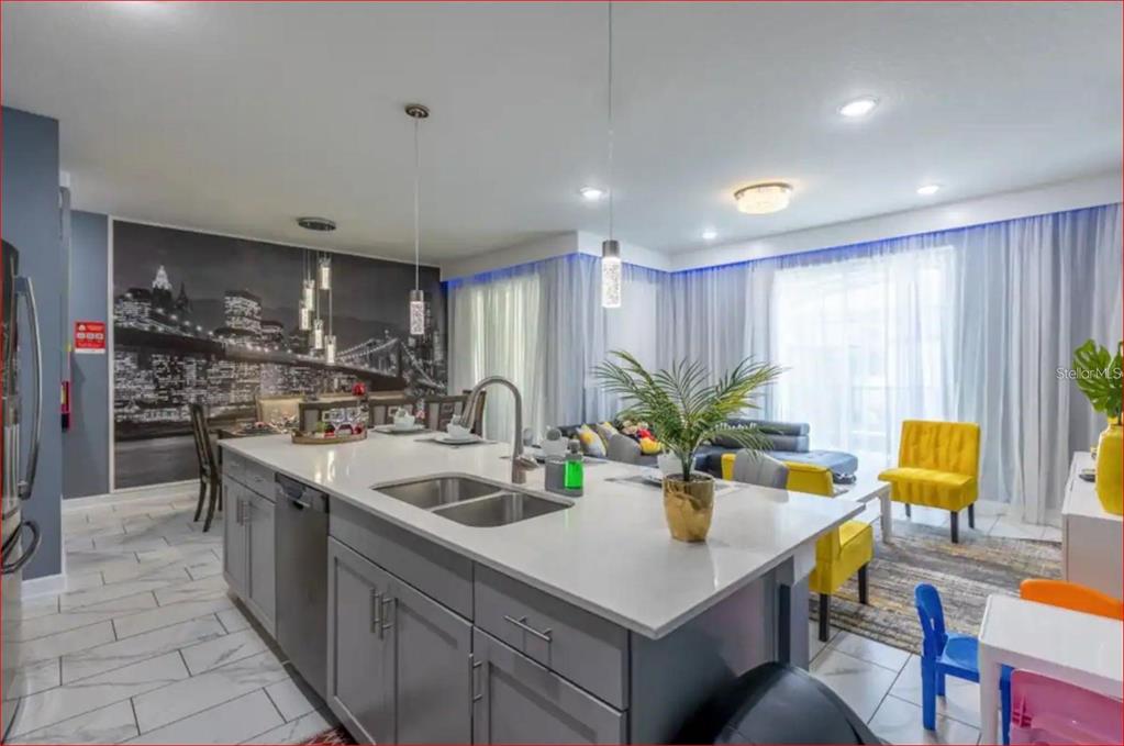A kitchen island with a sink sits in front of a living area with city-themed wallpaper — 1563 PLUNKER DRIVE, DAVENPORT, FL
