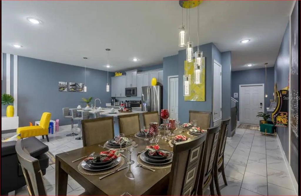 A dining area with a wooden table sits in front of an open kitchen — 1563 PLUNKER DRIVE, DAVENPORT, FL