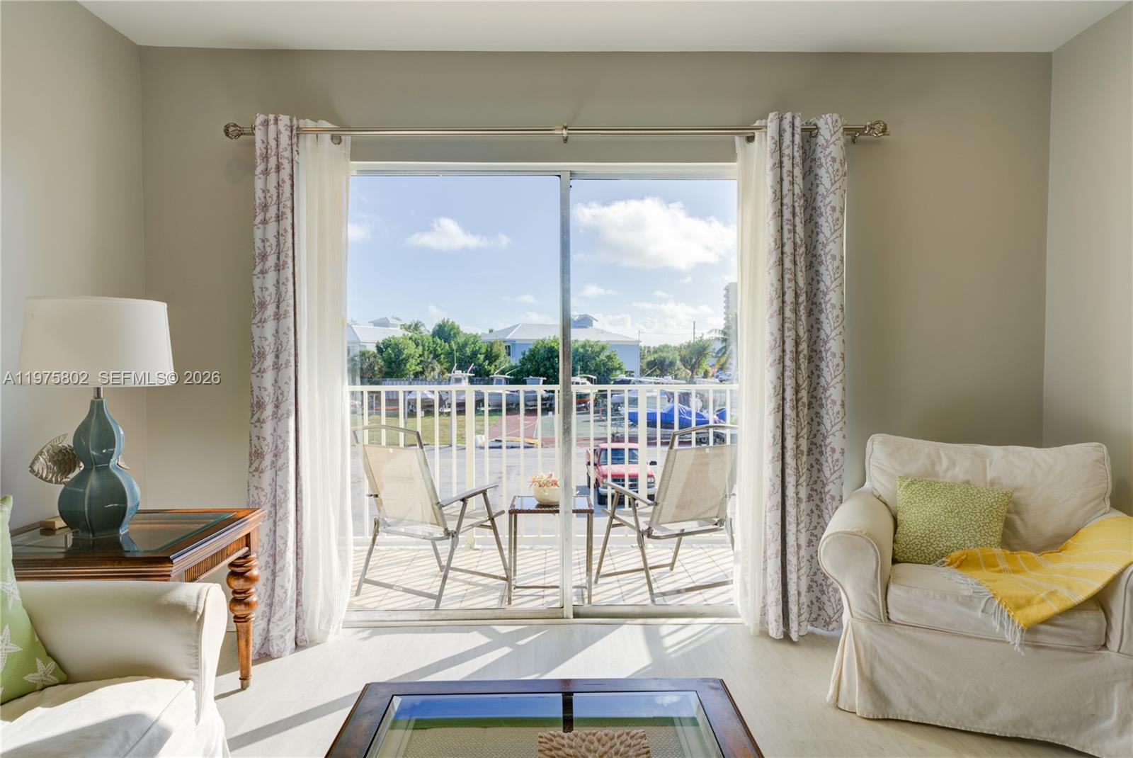 A living room features a sliding glass door opening onto a balcony with outdoor seating — 105 Avenue D # 113, Marathon FL 33050, MARATHON, FL
