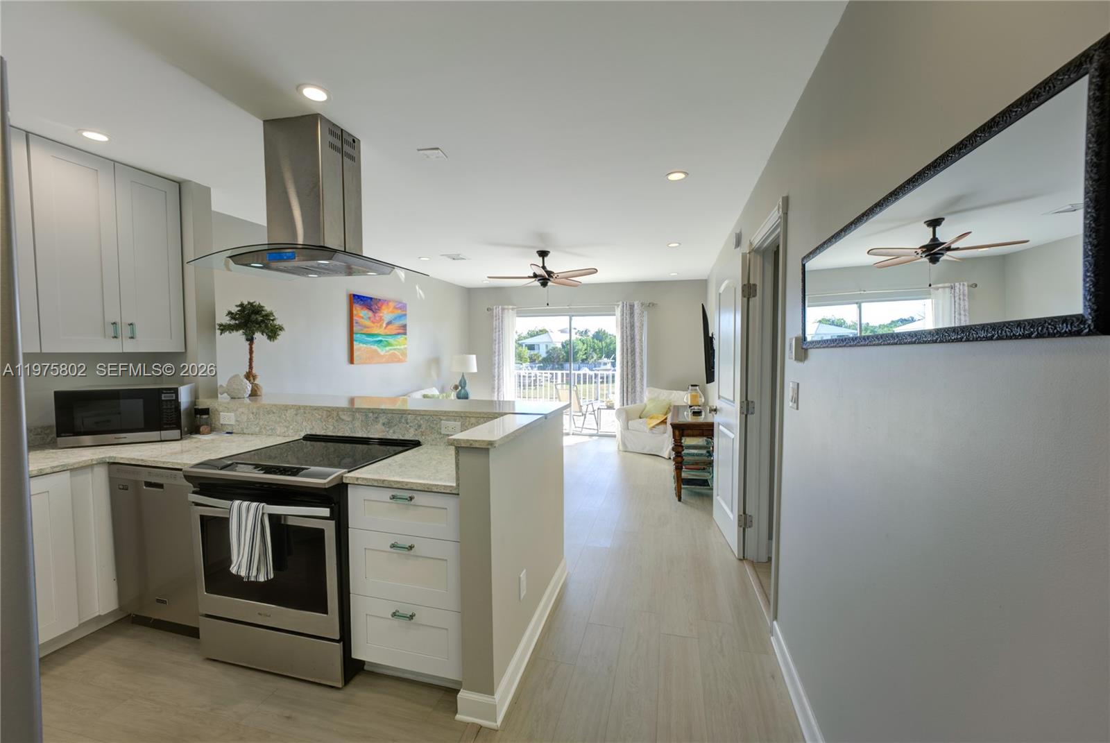 A kitchen with white cabinets and stainless steel appliances opens into a living area — 105 Avenue D # 113, Marathon FL 33050, MARATHON, FL