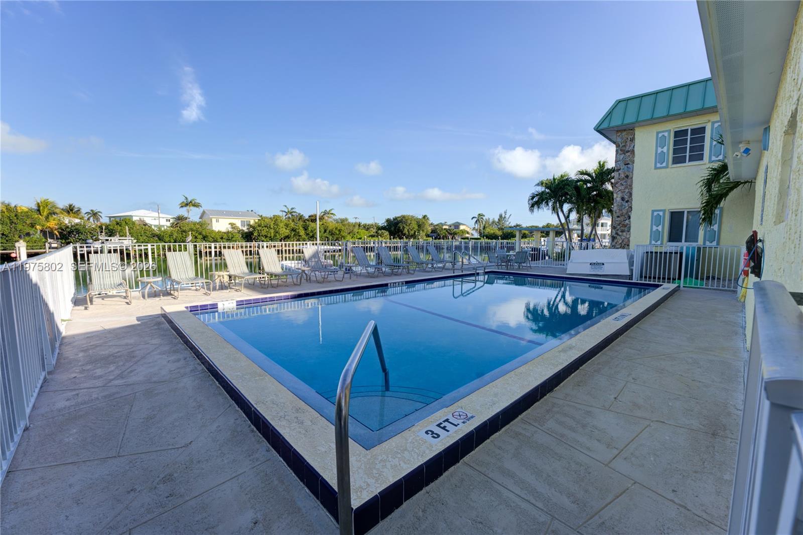 An outdoor swimming pool with lounge chairs sits beside a building with a green roof — 105 Avenue D # 113, Marathon FL 33050, MARATHON, FL