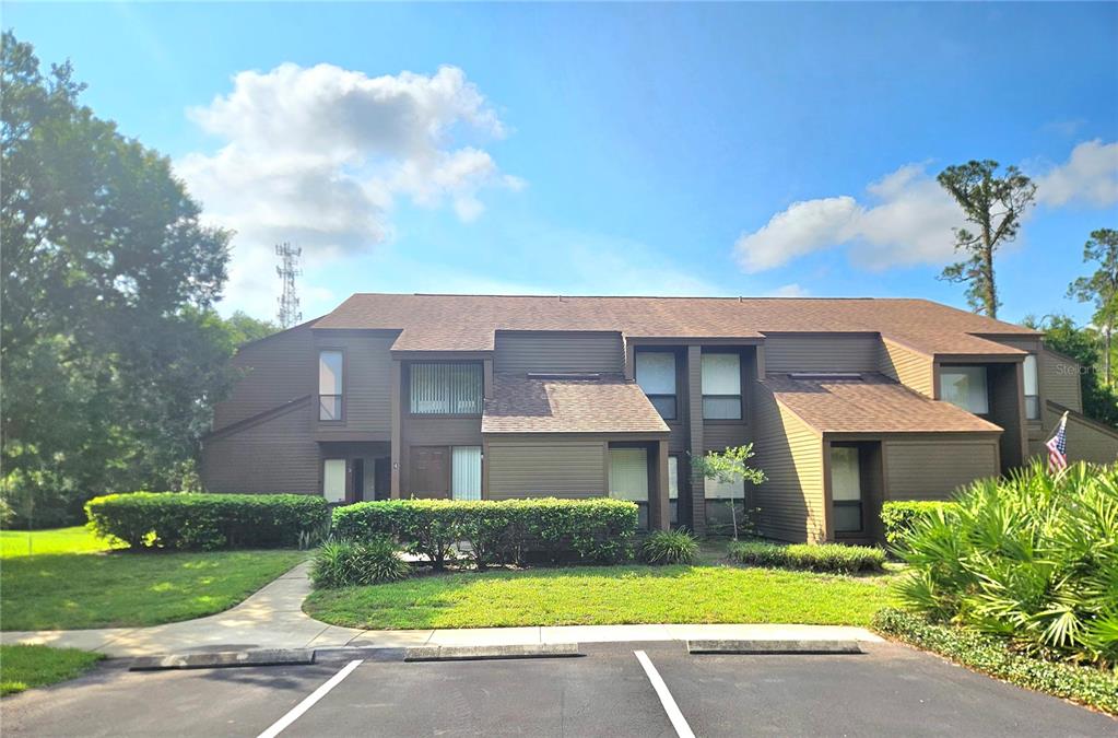 A two-story brown apartment building with a shingled roof sits behind a parking lot — 4 SHERBURY COURT UNIT 4, PALM COAST, FL