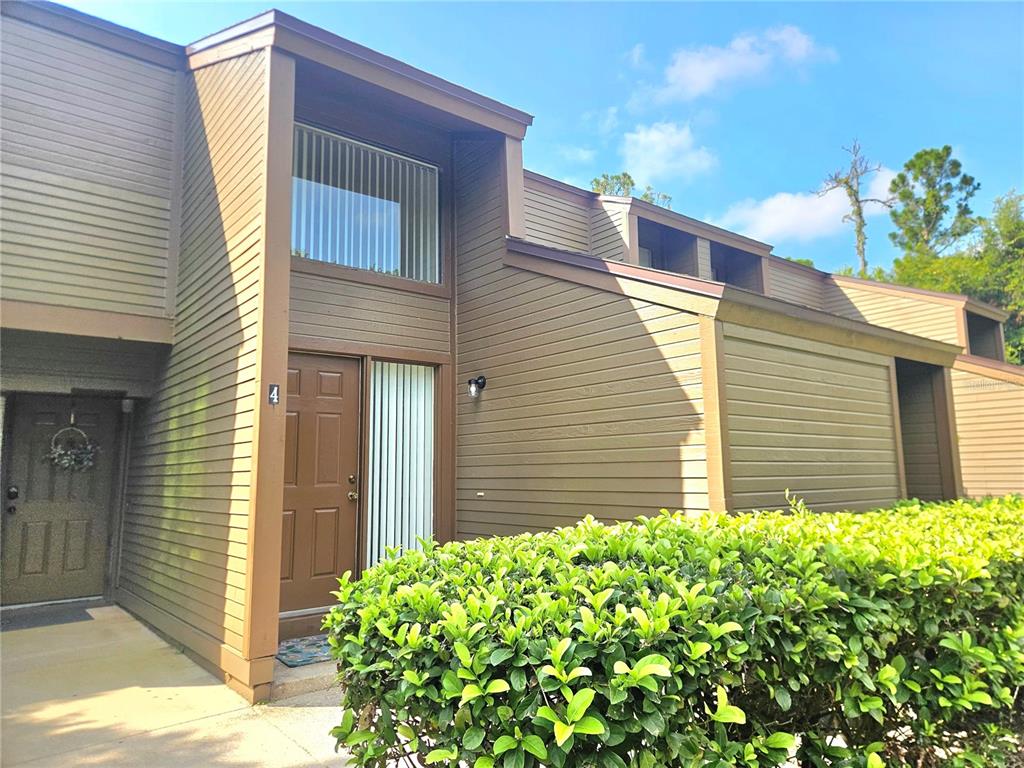 The exterior of a brown, multi-level townhouse features a front door marked with the number four — 4 SHERBURY COURT UNIT 4, PALM COAST, FL
