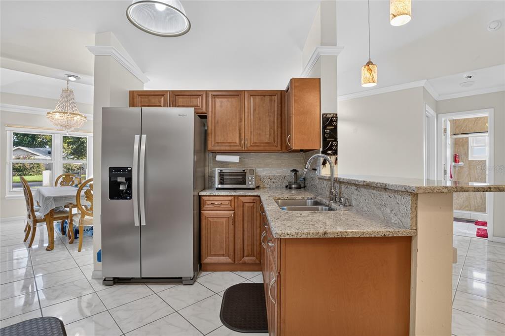 A kitchen features wood cabinets, granite countertops, stainless steel appliances, and tile flooring — 1435 LAMPLIGHTER WAY, ORLANDO, FL