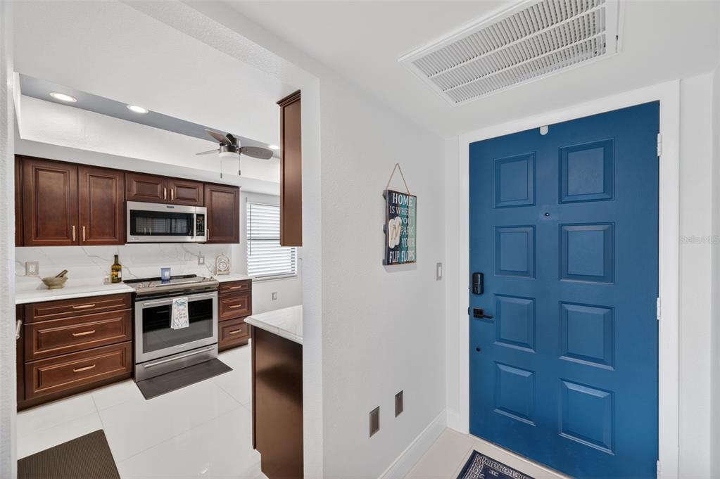 A view from an entryway looking into a kitchen with dark wood cabinets and appliances — 700 STARKEY ROAD UNIT 352, LARGO, FL