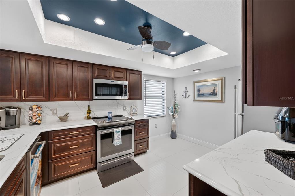 A kitchen features dark wood cabinets, white marble-style countertops, and a blue tray ceiling — 700 STARKEY ROAD UNIT 352, LARGO, FL
