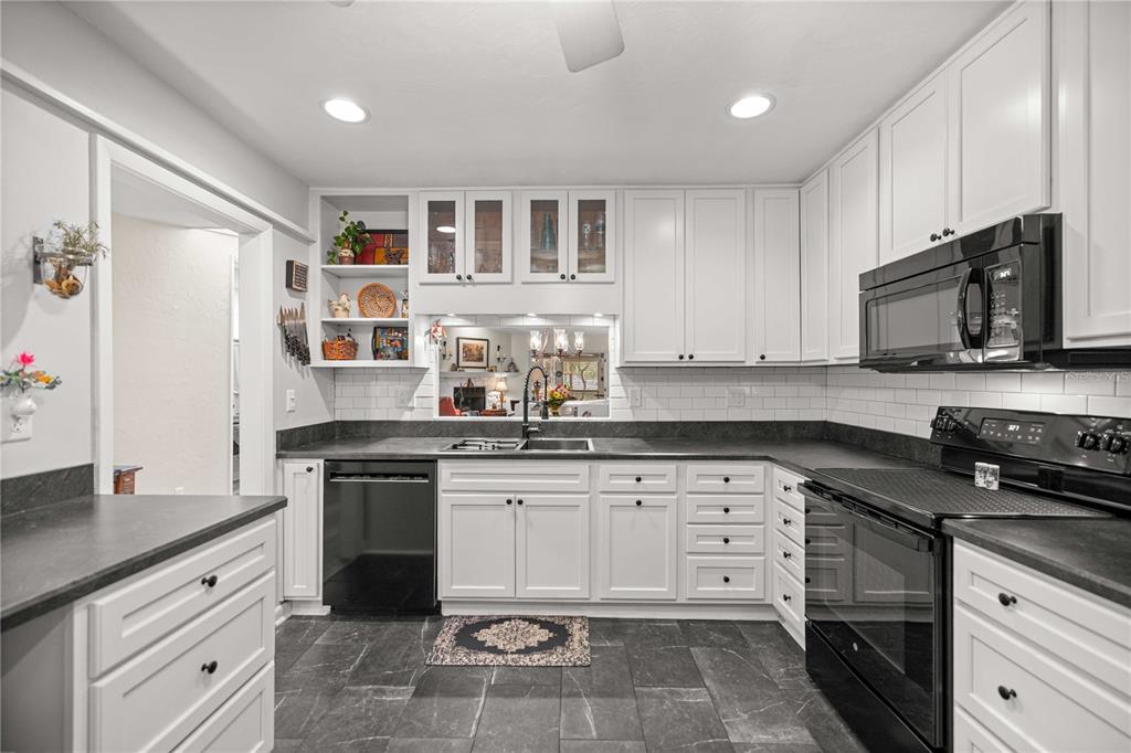 A kitchen with white cabinets, dark countertops, black appliances, and gray tile flooring — 1598 NW 19TH CIRCLE, GAINESVILLE, FL
