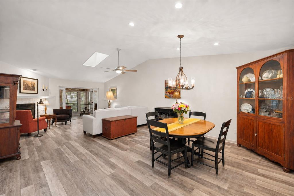 A living and dining room with wood-look flooring, a vaulted ceiling, and a wooden hutch — 1598 NW 19TH CIRCLE, GAINESVILLE, FL