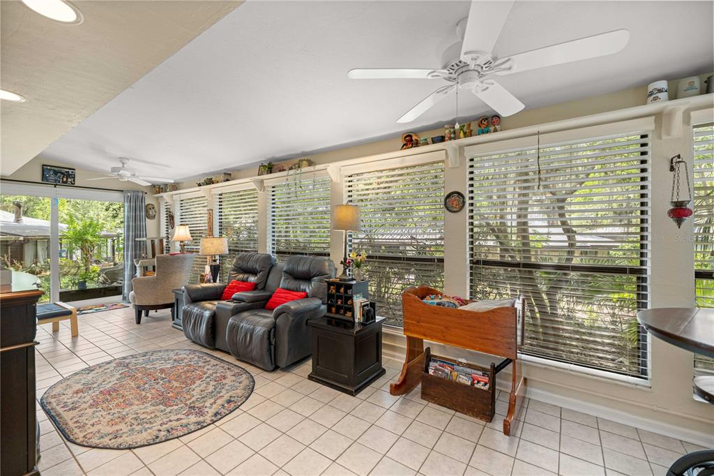 A sunroom features tile flooring, a ceiling fan, a loveseat, and large windows with blinds — 1598 NW 19TH CIRCLE, GAINESVILLE, FL