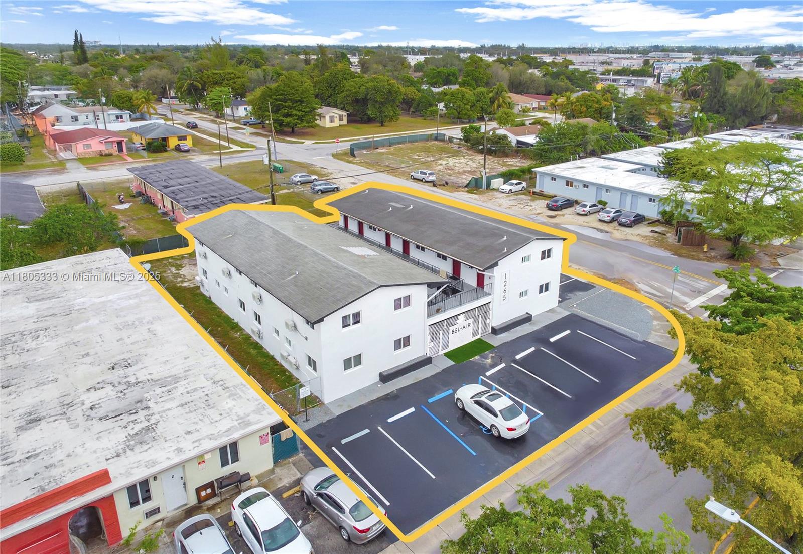 An aerial view shows a two-story apartment building with a parking lot and surrounding neighborhood — 1265 Sharazad Blvd, Opa-Locka FL 33054, OPA-LOCKA, FL