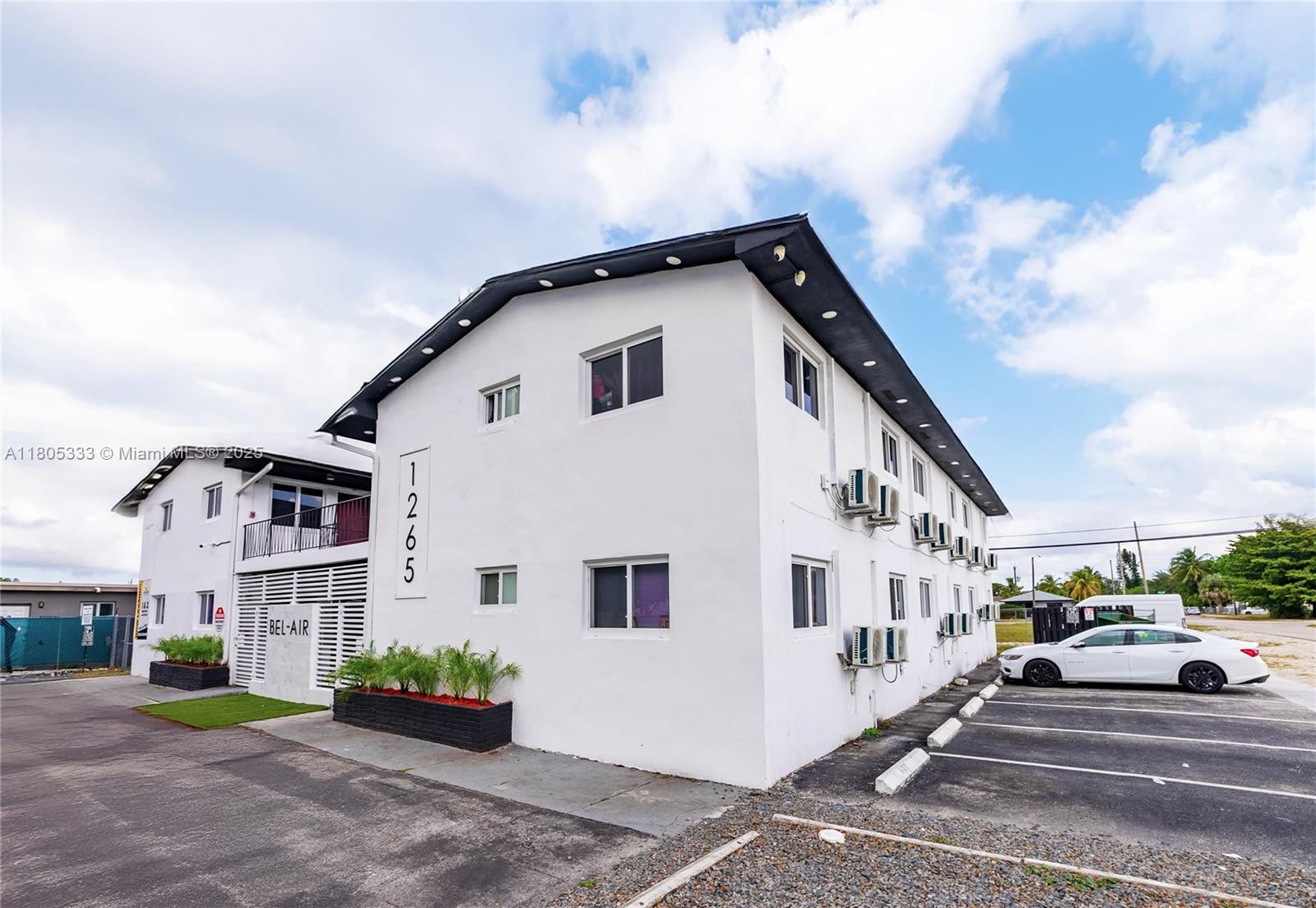 A white two-story apartment building with exterior air conditioning units and a parking lot — 1265 Sharazad Blvd, Opa-Locka FL 33054, OPA-LOCKA, FL