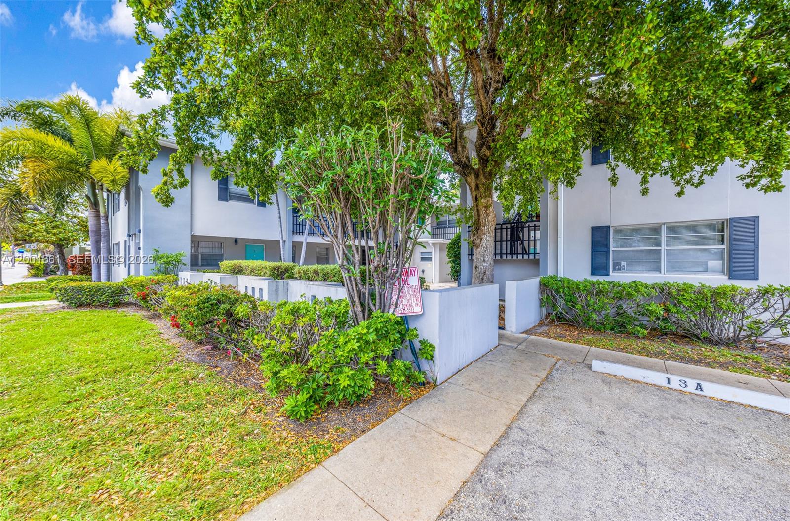 A two-story apartment building exterior features a concrete walkway, landscaping, and a parking space — 202 Lucerne Ave # 14, Lake Worth FL 33460, LAKE WORTH, FL