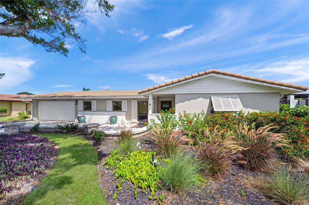 A single-story house with a white garage, gray siding, and a landscaped front yard — 549 HALYARD LANE, LONGBOAT KEY, FL
