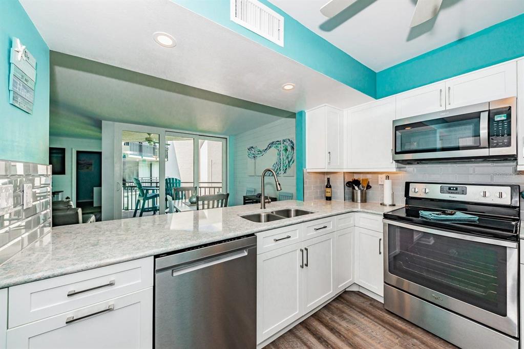 A kitchen with white cabinets, stainless steel appliances, and granite countertops overlooks a balcony — 5505 PUERTA DEL SOL BOULEVARD S UNIT 325, ST PETERSBURG, FL