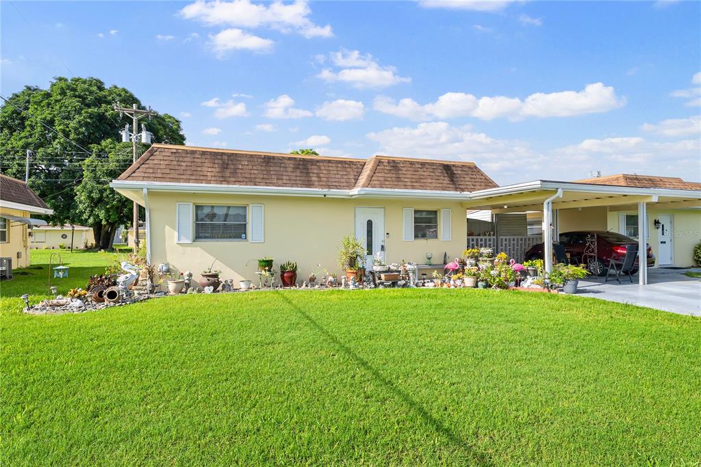 A single-story yellow house with a brown shingled roof and an attached carport — 2208 GARDENIA WAY, LEHIGH ACRES, FL