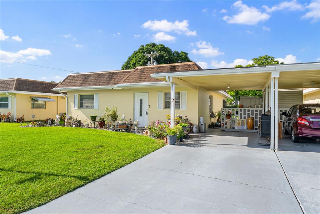 A single-story house with a yellow exterior, a brown roof, and an attached carport — 2208 GARDENIA WAY, LEHIGH ACRES, FL