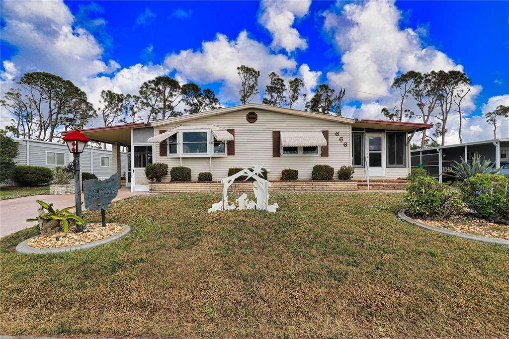 A single-story manufactured home features light siding, a bay window, and a front yard nativity — 666 ALVARADO, NORTH PORT, FL