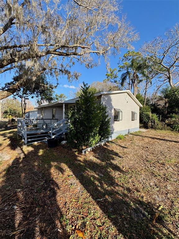 A light-colored mobile home with a wooden deck sits on a dry, grassy lot — 7700 VINE STREET, LAND O LAKES, FL