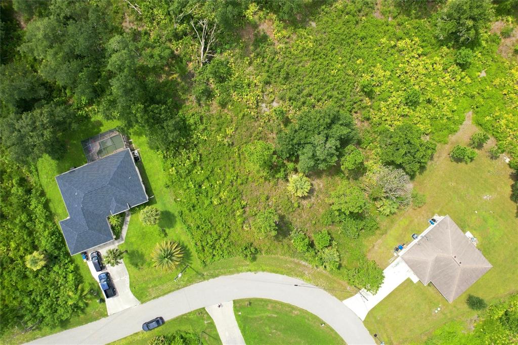 An aerial view shows two houses situated on large, wooded lots along a curved road — NYBERG ROAD, NORTH PORT, FL