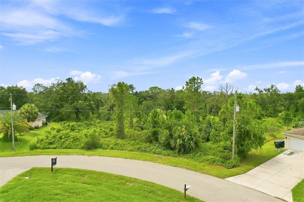 An elevated view of a vacant, tree-covered lot situated between two residential houses — NYBERG ROAD, NORTH PORT, FL
