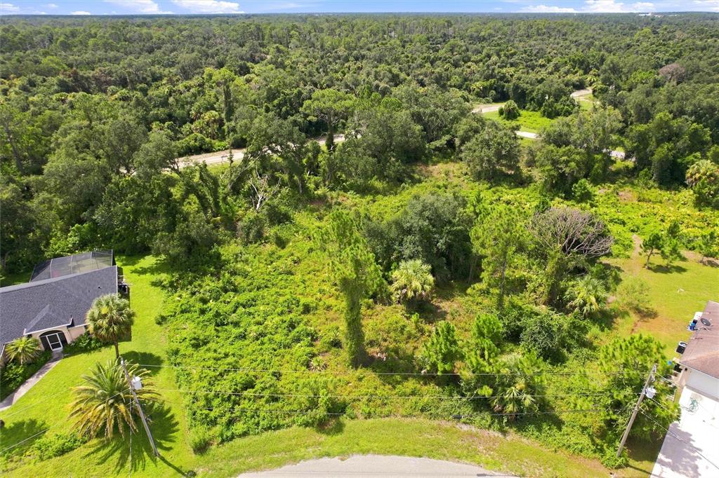 An aerial view shows a vacant, wooded residential lot situated between two existing houses — NYBERG ROAD, NORTH PORT, FL
