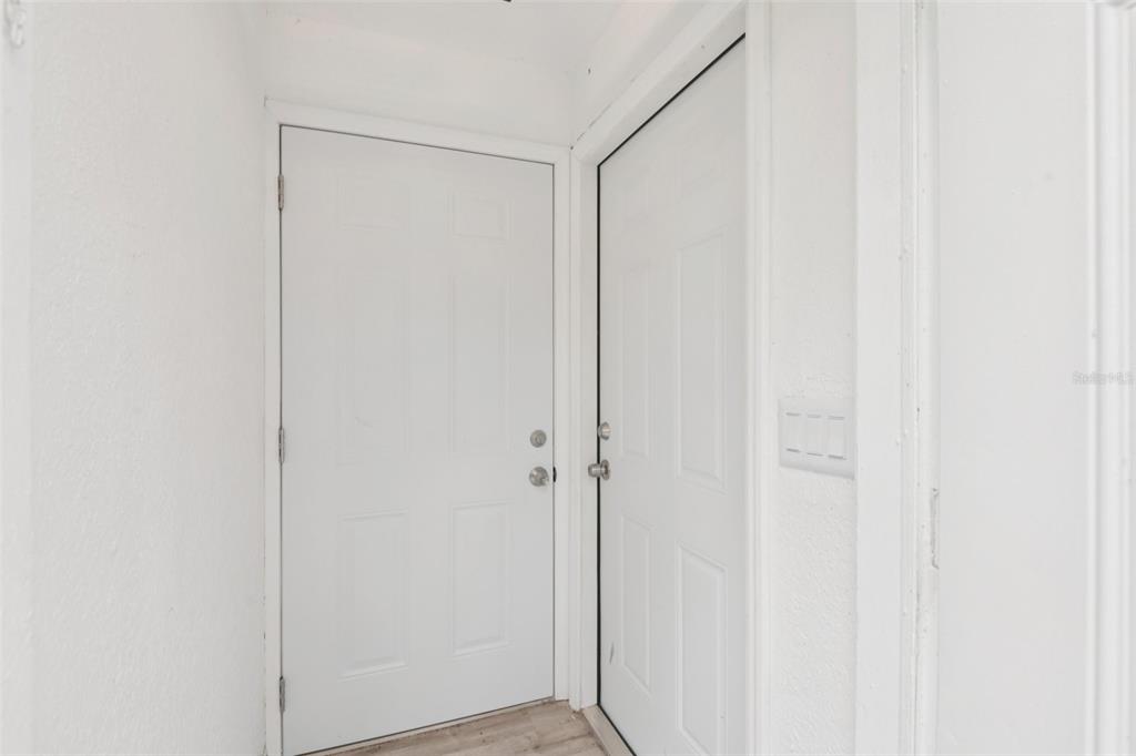A narrow hallway features two white doors and light-colored wood-look flooring — 9404 N MULBERRY STREET, TAMPA, FL