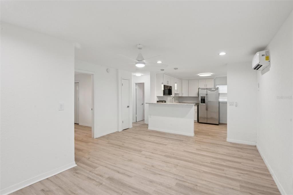 An open-concept living area with light wood flooring, a kitchen island, and white cabinetry — 9404 N MULBERRY STREET, TAMPA, FL