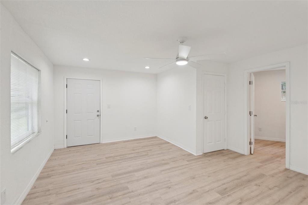 A bright room with white walls, light wood-look flooring, a ceiling fan, and two doors — 9404 N MULBERRY STREET, TAMPA, FL
