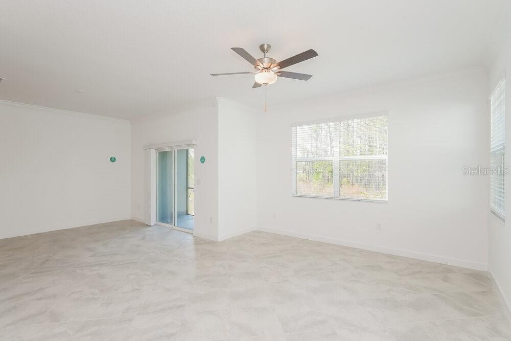 An empty room with white walls, tile flooring, a ceiling fan, and a sliding glass door — 17512 RADIANT SHINE WAY, LUTZ, FL