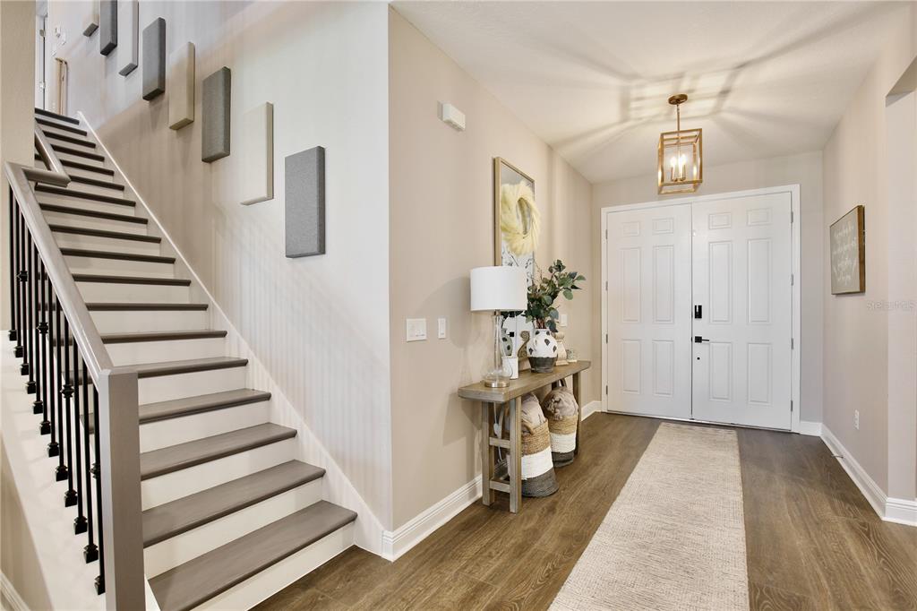 An entryway features a staircase with dark wood treads, a console table, and double doors — 4861 CRAGMERE LOOP, CLERMONT, FL