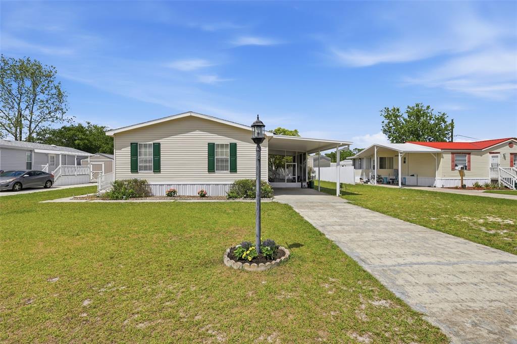 A single-story manufactured home with light siding, green shutters, and a concrete driveway — 373 DOLORES BOULEVARD, DELAND, FL