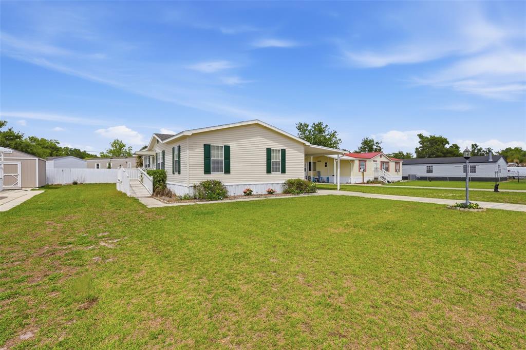 A light-colored manufactured home with green shutters sits on a grassy lot — 373 DOLORES BOULEVARD, DELAND, FL
