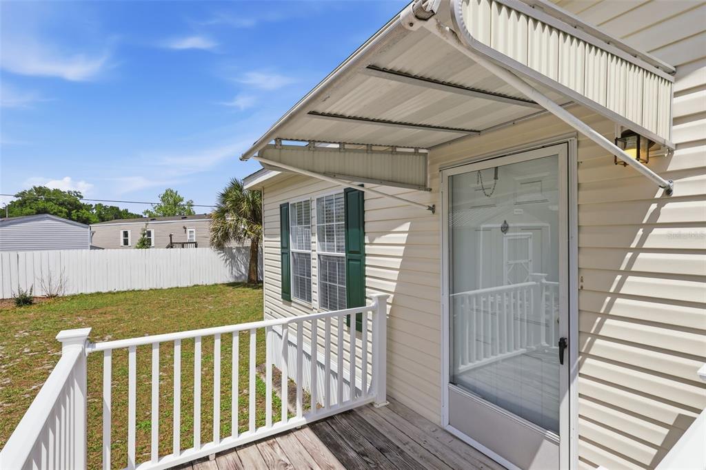 A wooden deck with a white railing and metal awning sits outside a mobile home — 373 DOLORES BOULEVARD, DELAND, FL