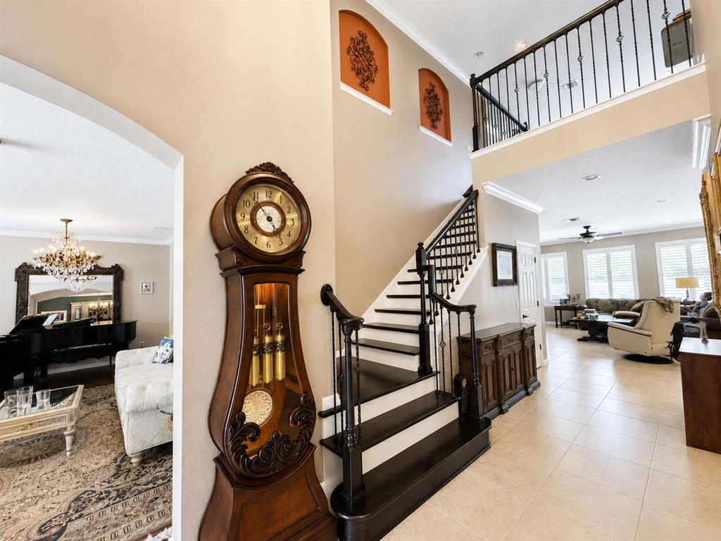 A grand foyer features a tall grandfather clock, a dark wood staircase, and tiled floors — 1442 VIVALDI PLACE, LONGWOOD, FL