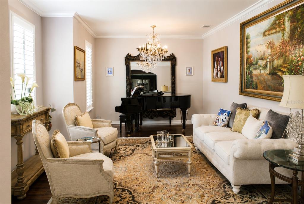 A formal living room features a grand piano, crystal chandelier, ornate rug, and traditional furniture — 1442 VIVALDI PLACE, LONGWOOD, FL