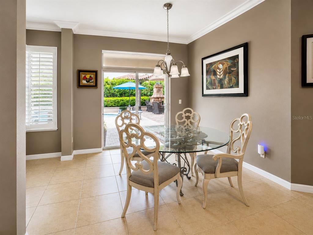 A dining area with a glass table, four chairs, and a sliding door to a patio — 1442 VIVALDI PLACE, LONGWOOD, FL