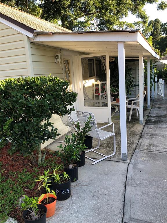 A covered patio area features white metal chairs and several potted plants on a concrete walkway — 5226 BRAFORD ROAD, APOPKA, FL