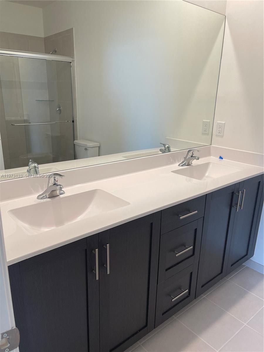 A bathroom features a double-sink vanity with dark cabinets, a white countertop, and a large mirror — 20564 NE 5th Pl, Miami FL 33179, MIAMI, FL