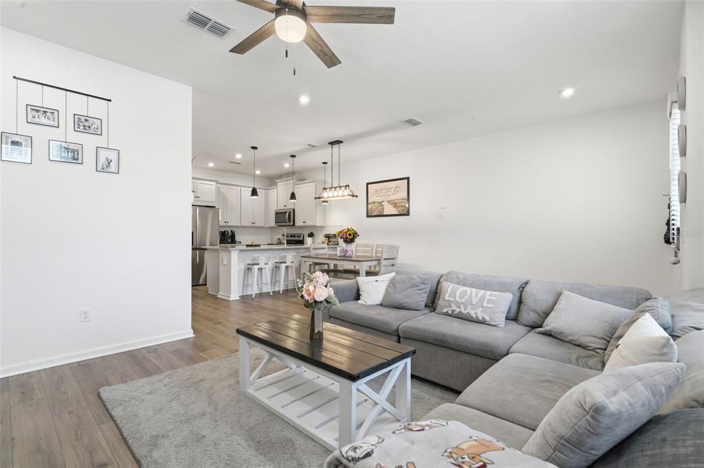 A living room with a gray sectional sofa and coffee table opens to a kitchen — 11429 SUNSAIL AVENUE, ORLANDO, FL